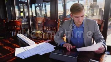 在咖啡馆里准<strong>备考</strong>试前的年轻学生，拿着试卷和平板电脑