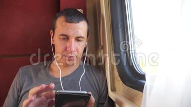 男子听音乐在火车上旅行，<strong>火车车厢</strong>车厢旅行。 慢动作视频。 一个男人