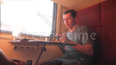 男人坐在火车车厢上，手里拿着智能手机铁路，喝着咖啡和茶。 慢生活方式慢生活方式