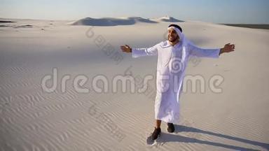 快乐的阿拉伯阿联酋酋长国男人走在白色沙漠中间，在炎热的夏天享受生活。
