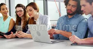 商务主管在会议中使用笔记本电脑、手机和数码平板电脑
