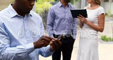 行政人员在同事使用数码平板电脑时使用手机