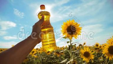 农夫手里拿着一瓶塑料<strong>葵花籽</strong>油，阳光洒在他的手里。 慢动作视频。 蓝天背景