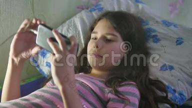 女孩<strong>玩</strong>智能<strong>手机</strong>、网络游戏、社交媒体躺在室内的<strong>床上</strong>