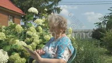 年长的祖母拿着银数字平板电脑