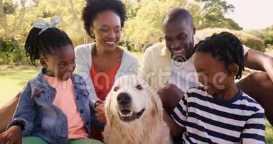 可爱家庭的肖像是微笑的，和一只狗坐在一起
