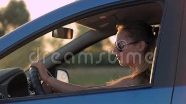 美丽的年轻女子坐在车里，<strong>驶入</strong>夕阳。