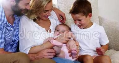 可爱的一家人坐在沙发上抱着一个孩子