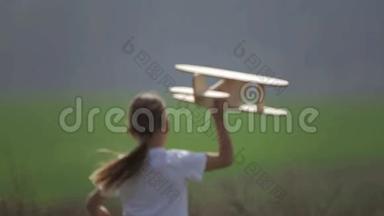白人男孩玩模型飞机。 一个在田野里坐木飞机的孩子的肖像。