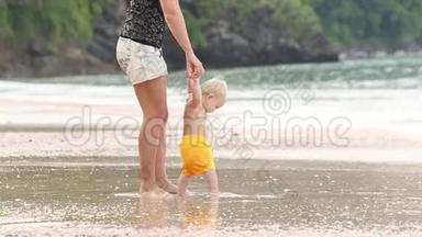 孩子在海滩上和他妈妈一起经过把手