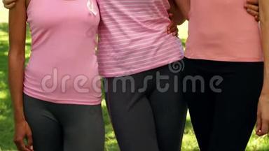 在公园里，穿着粉色衣服的女士微笑，以提高对乳腺癌的认识