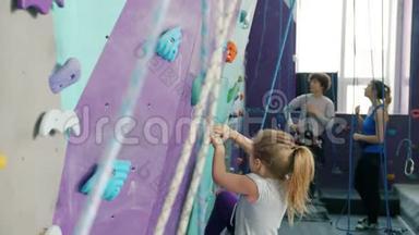 小女孩在攀岩运动中爬人造墙，享受极限活动