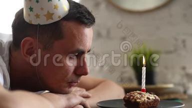 体贴的悲伤的人坐在小蛋糕前面点燃蜡烛。