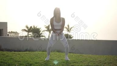 一个迷人的年轻女人在户外做肌肉伸展。 在用棕榈树慢跑前热身