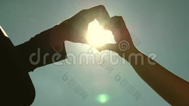 手里拿着太阳。 一对<strong>恩爱</strong>夫妻的剪影，用双手在地平线上的太阳对面做一个心的象征