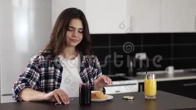 检疫期间厨房里的年轻女子。 坐在<strong>桌子</strong>旁，在烤面包上放些果酱。 早上吃美味的<strong>早餐</strong>。