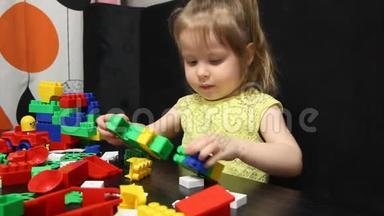 三岁的女孩在玩一个建设者的彩色积木。 孩子培养自己的思维能力.. 发展和发展