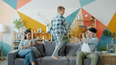 父亲和儿子在家里玩智能手机时享受枕头大战