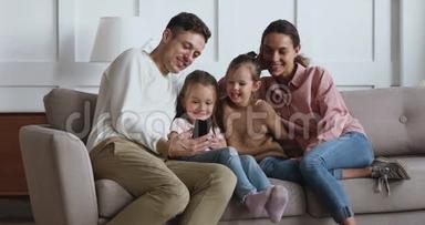 微笑的年轻父亲与孩子和妻子录制视频。