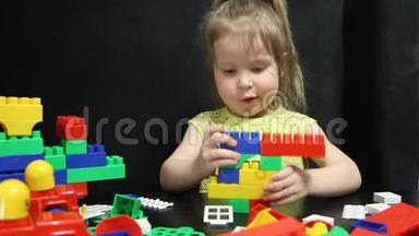 三岁的女孩在玩一个建设者的彩色积木。 孩子培养自己的思维能力.. 发展和发展