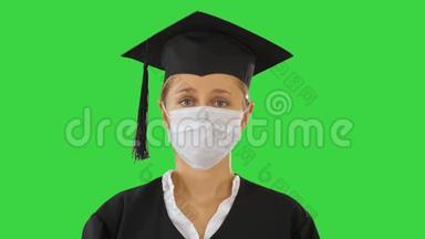 研究生女士戴着医疗面具，在绿色屏幕上寻找相机，色度键。