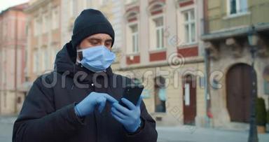 男人在使用智能手机时戴着医用口罩和手套打字。 一个戴着防护面具的人独自站着