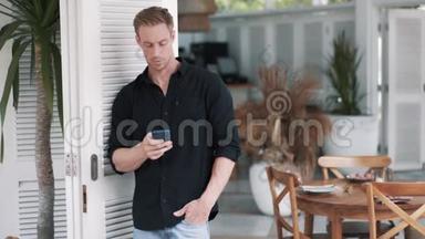 穿衬衫的帅哥站在时尚的咖啡馆里，用电话发信息