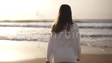 布鲁内特女士独自在沙滩上散步。 穿着休闲服装在海边或海边沙滩上散步的女孩