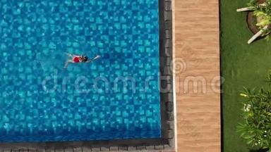 从顶部看，女人穿着红色比基尼在游泳池里蛙泳，然后走出游泳池。 运动女游泳运动员