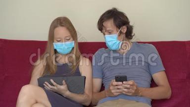 一个年轻的男人和女人在自我隔离期间坐在家里的沙发上上网。 他们戴着医用口罩