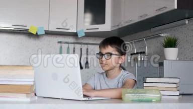 带着课本在学校做作业的男孩在家里用笔记本电脑。 在线<strong>学习</strong>、<strong>远程学习</strong>、家庭教育