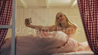 在宿舍房间里，一位年轻漂亮的女士坐在床上，用智能手机进行视频聊天