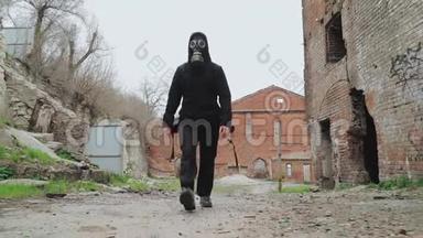 戴着防毒面具和黑色衣服的男人背着一个背包在前城的废墟中行走。