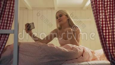 在宿舍房间里，一位年轻漂亮的女士坐在床上，用智能手机进行视频聊天