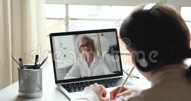 年长的女在线老师在笔记本电脑屏幕上上远程课