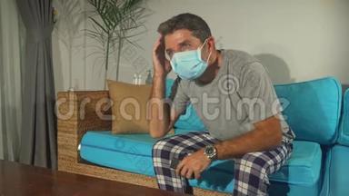 Covid-19病毒恐慌锁定-悲伤和焦虑的男人戴着医疗面具，看电视新闻冠状病毒爆发