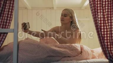 在<strong>宿舍</strong>房间里，一位年轻漂亮的女士坐在床<strong>上</strong>，用智能手机进行视频聊天