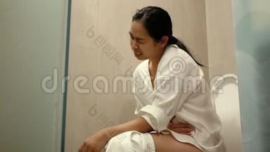 年轻的亚洲女人在家里的马桶上<strong>便秘</strong>。 保健概念。