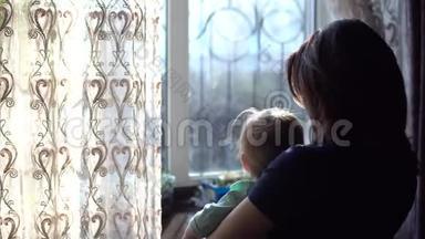 一位年轻的母亲抱<strong>着</strong>一个婴儿。 一个女人带<strong>着</strong>一个孩子<strong>看着窗外</strong>推<strong>着</strong>窗帘。