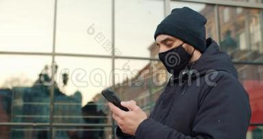 侧面观看男子戴黑色棉防护面具使用智能<strong>手机</strong>。 打字，<strong>滚动</strong>和触摸<strong>手机</strong>屏幕