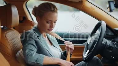 注意力集中的女人在驾驶座上扣安全带。 坐在豪华车旁的女孩。