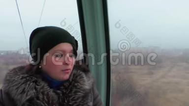 女孩坐在机舱缆车里，<strong>看</strong>着<strong>窗外</strong>。