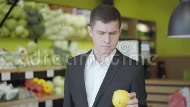 自信认真的男人在<strong>超市</strong>挑选梨的肖像。 年轻的白人选择黄色<strong>水果</strong>出售