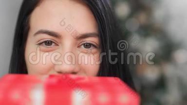 极端近脸滑稽的亚洲女人摆着喜庆的红色礼品盒。 4k龙红相机