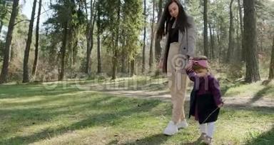 快乐的小女孩在针叶林的树上和妈妈散步玩耍。 健康儿童家庭娱乐