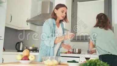 两个年轻漂亮的女人在明亮的厨房里<strong>忙着</strong>做饭。