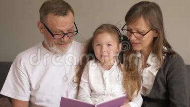 可<strong>爱的</strong>祖父母和他们<strong>的</strong>孙子坐在书上一起读有趣<strong>的故事的</strong>画像