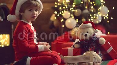 冬季圣诞节孩子们的情感。 新年孩子。 可爱的孩子玩圣诞礼物。 圣诞老人帽子上的可爱孩子