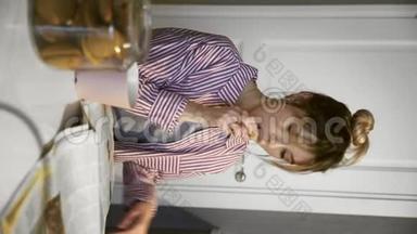 年轻美丽的黑发女人在厨房里喝咖啡，吃饼干，<strong>看报</strong>纸的垂直视频