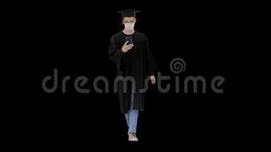 戴着毕业礼服戴着医疗面具的年轻人使用智能手机，阿尔法频道